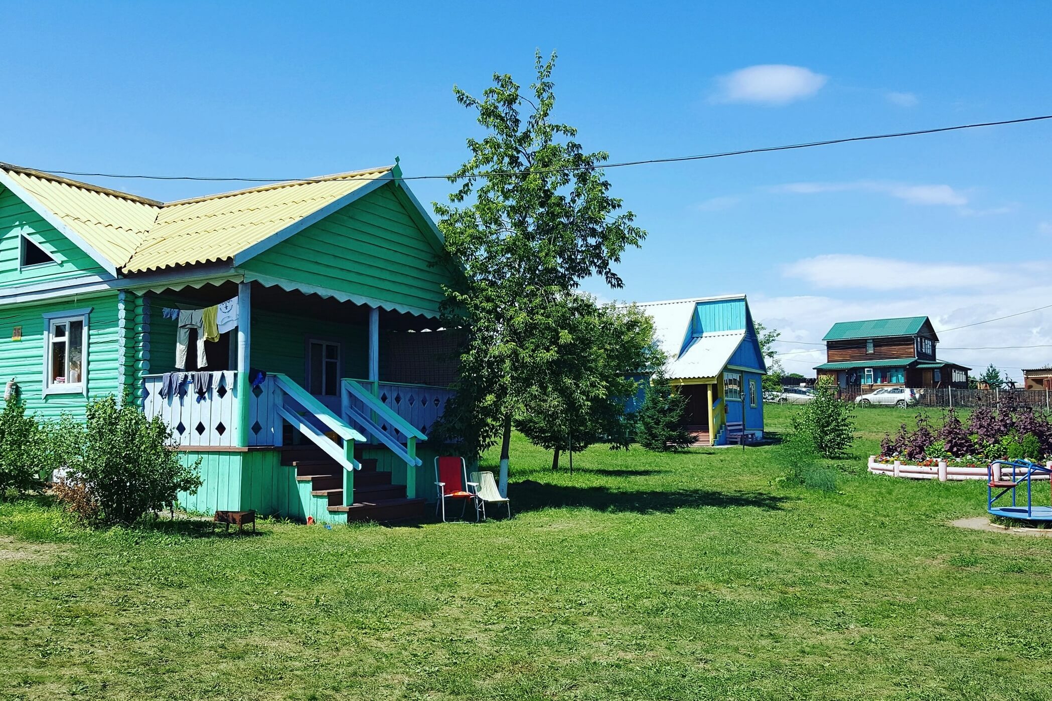 Деревянные, одноэтажные домики. Зеленый газон перед крыльцом.