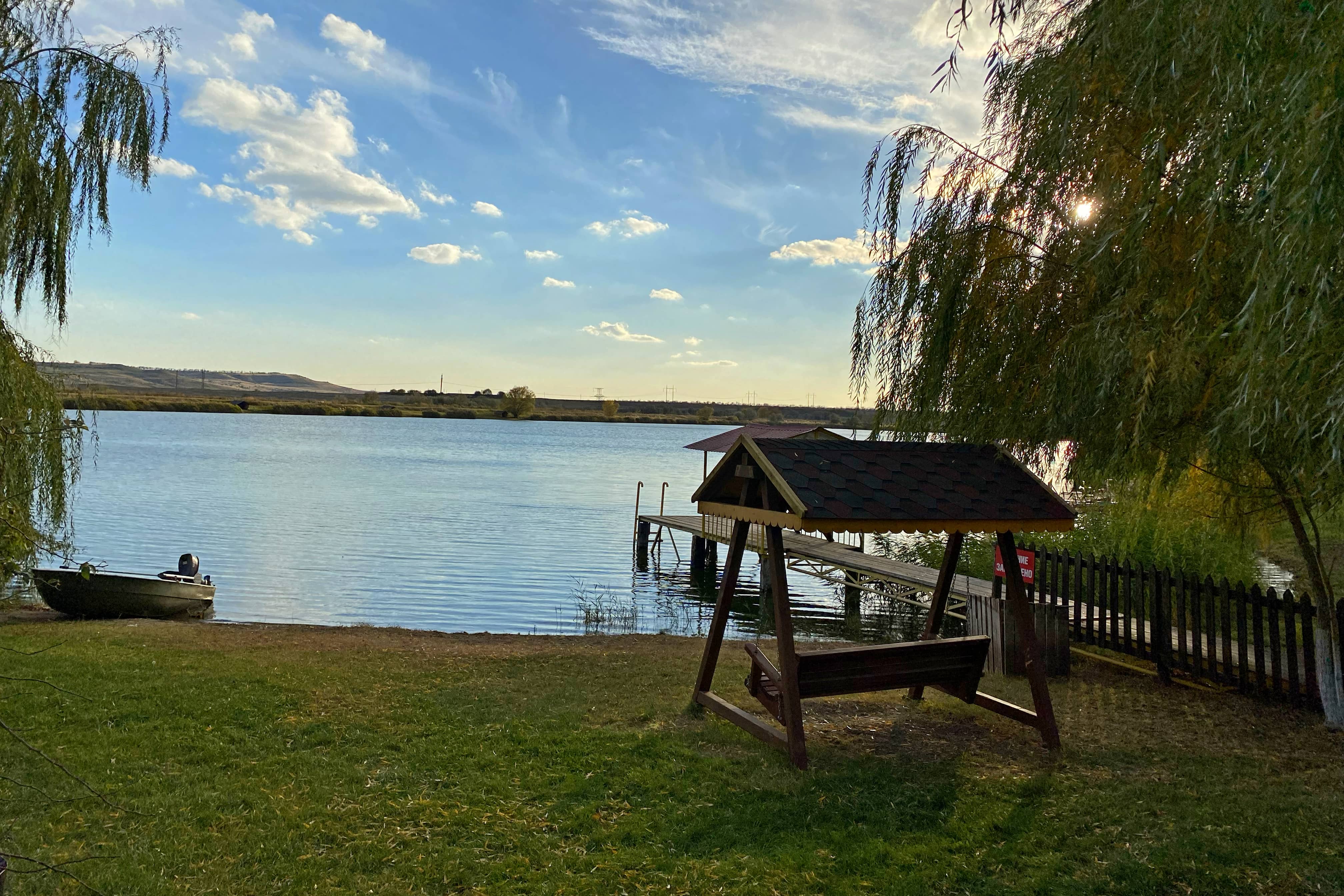 Качели с видом на воду, лодка и пирс.