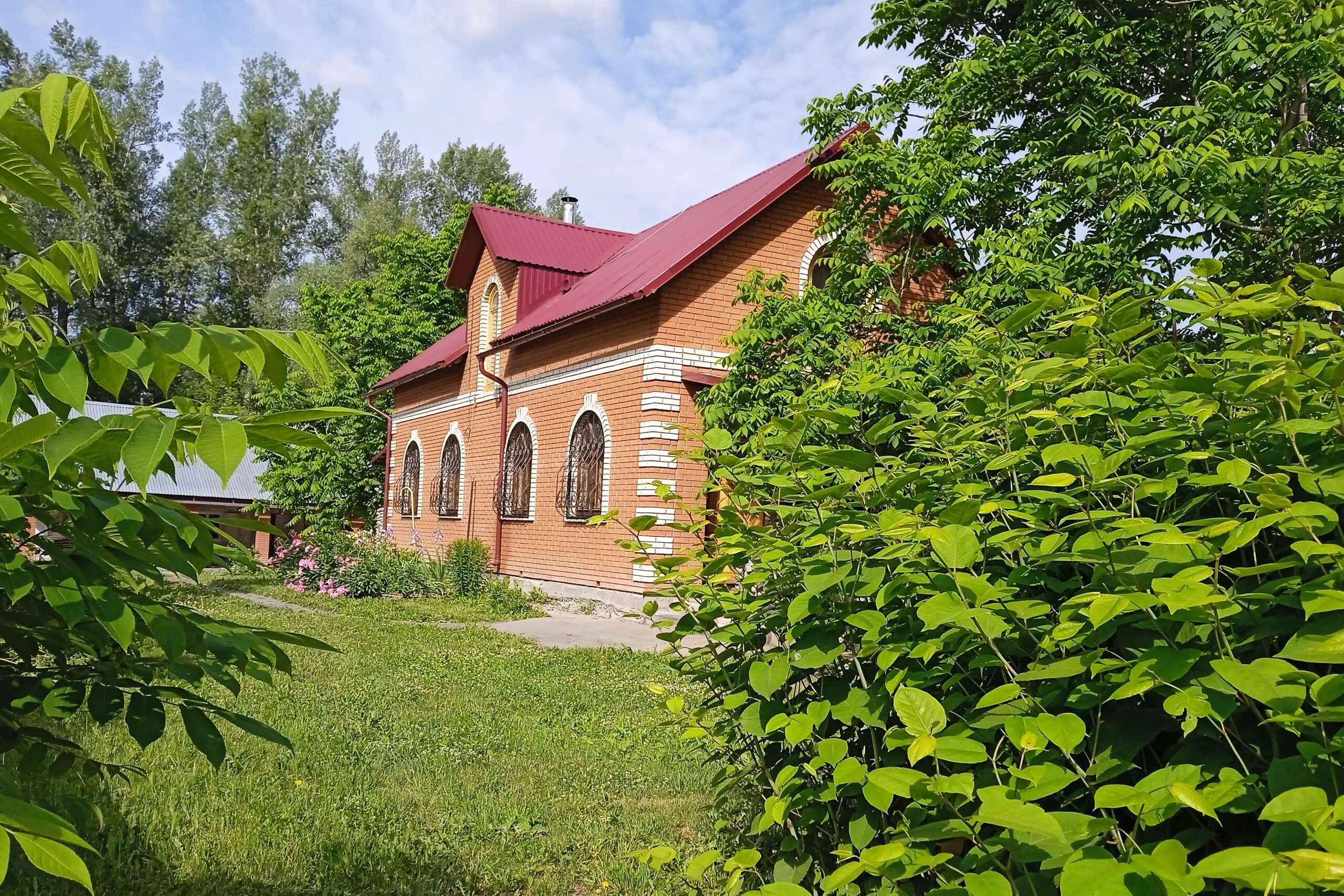 Дом из кирпича и зеленая лужайка рядом с ним.