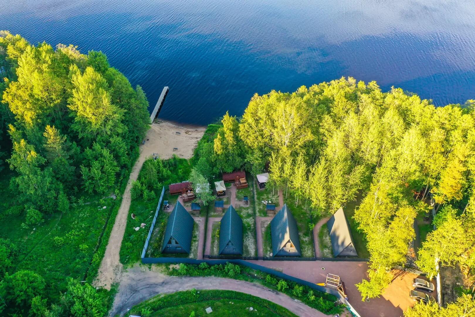 Панорамный вид: домики, лес и озеро.