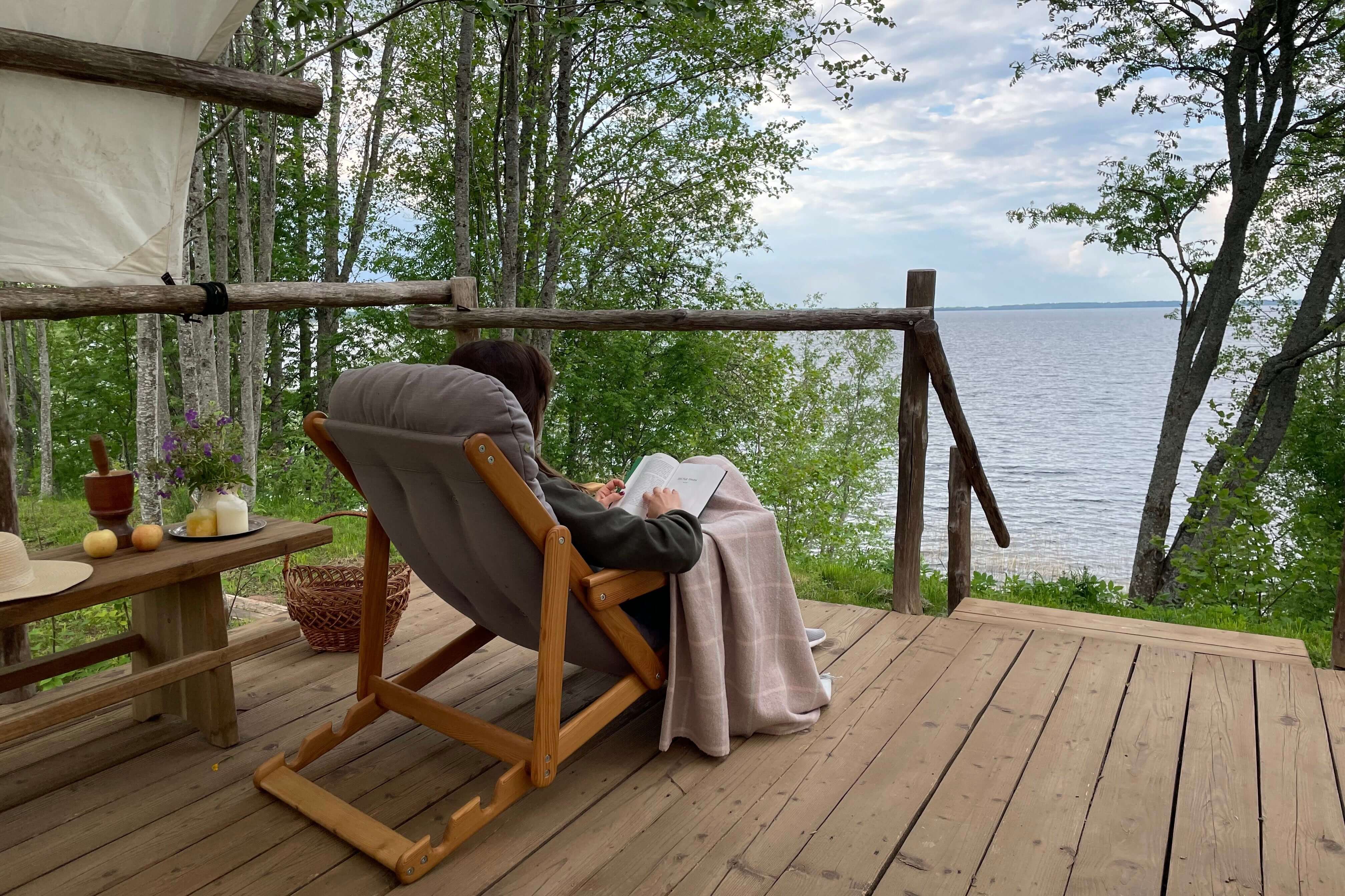 Отличное место для отдыха с книгой в руках сидя в кресле на террасе домика.