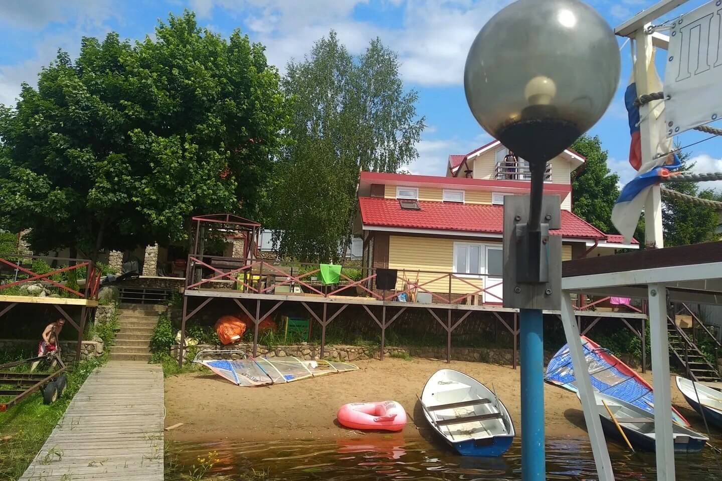 Причал, дом с террасой на берегу, пришвартованные старые лодки.