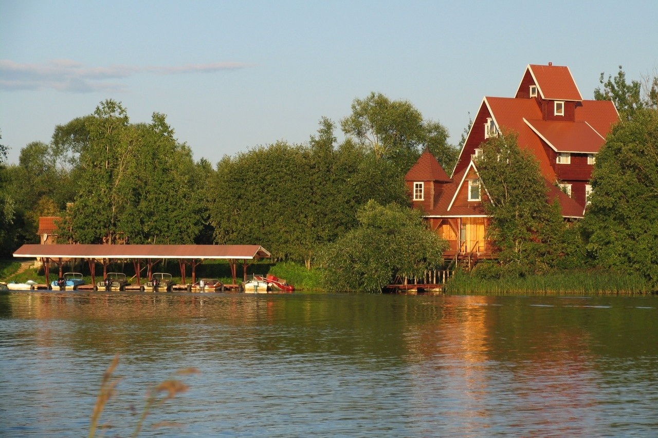 Вид с воды: берег, пирс и большой гостевой коттедж.